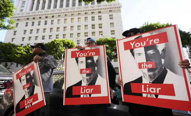 Supporters hold signs with images of District Attorney Nathan Hochman during a press conference regarding developments in the Menendez brothers case Thursday, March 20, 2025, in Los Angeles. (AP Photo/Damian Dovarganes)