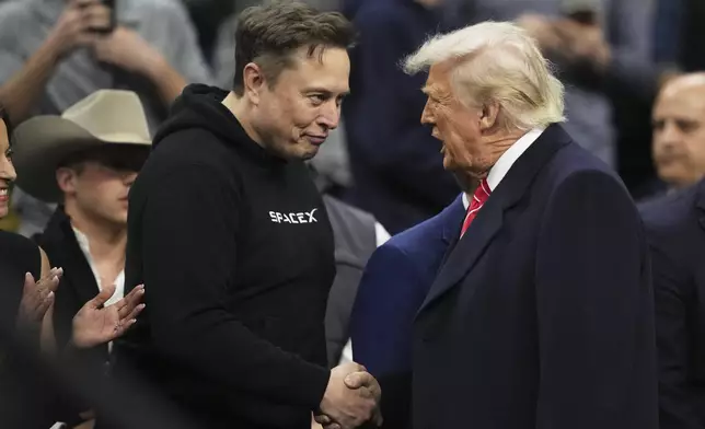 Elon Musk, left, shakes hands with President Donald Trump at the finals for the NCAA wrestling championship, Saturday, March 22, 2025, in Philadelphia. (AP Photo/Matt Rourke)
