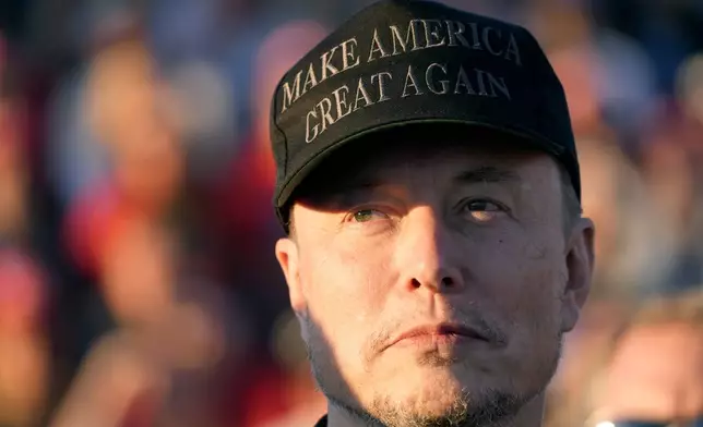 FILE - Tesla and SpaceX CEO Elon Musk listens as Republican presidential nominee former President Donald Trump speaks at a campaign event at the Butler Farm Show, Oct. 5, 2024, in Butler, Pa. (AP Photo/Alex Brandon, File)