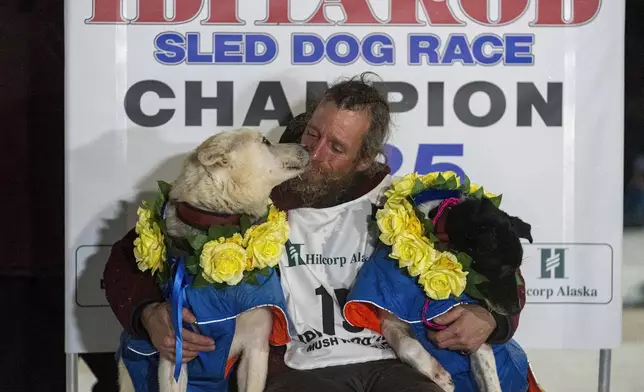 Jessie Holmes hugs his lead dogs Polar, left, and Hercules after winning the Iditarod Trail Sled Dog Race early Friday morning, March 14, 2025 in Nome. (Loren Holme/Anchorage Daily News via AP)