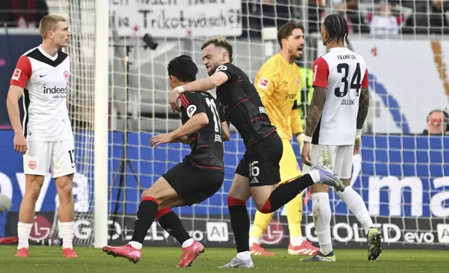 Union Berlin's Wooyeong Jeong, second left, celebrates scoring with teammate Benedict Hollerbach during the German Bundesliga soccer match between Eintracht Frankfurt and 1. FC Union Berlin at Deutsche Bank Park, in Frankfurt, Germany, Sunday, March 9, 2025. (Arne Dedert/dpa via AP)