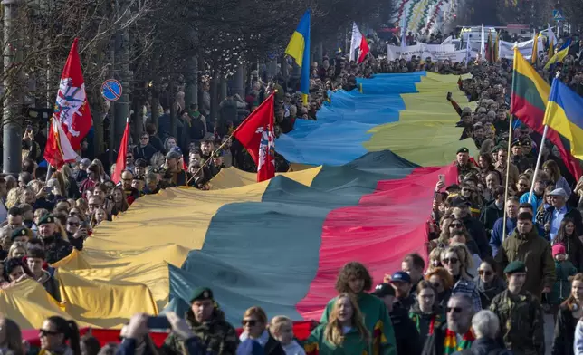 People carry a giant Ukrainian and Lithuanian flags, front, to protest against the Russian invasion of Ukraine during a celebration for the 35th anniversary of Lithuania's independence from the Soviet Union in Vilnius, Lithuania, Tuesday, March 11, 2025. (AP Photo/Mindaugas Kulbis)