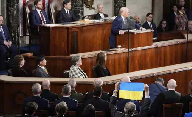 A member of Congress holds up Ukraine's flag as President Donald Trump addresses a joint session of Congress at the Capitol in Washington, Tuesday, March 4, 2025. (AP Photo/Alex Brandon)