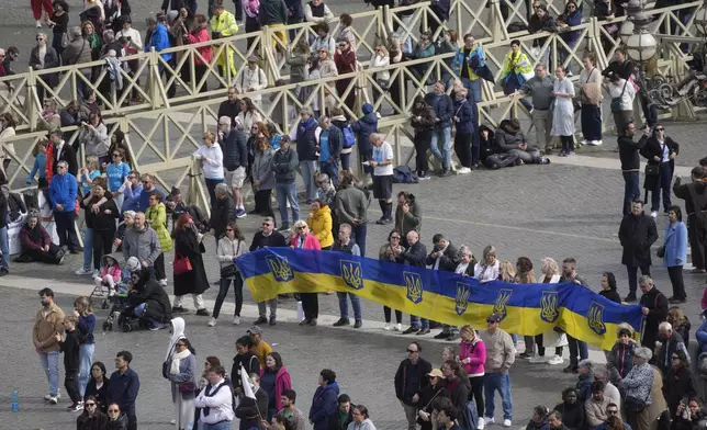 Faithful hold Ukrainian national flags as Cardinal Michael Czerny, prefect of the Dicastery for Promoting Integral Human Development, and delegate of Pope Francis celebrates a mass for the members of the world of volunteers in St. Peter's Square at The Vatican, Sunday, March 9, 2025. (AP Photo/Gregorio Borgia)