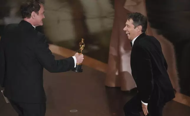 Quentin Tarantino, left, presents the award for best director to Sean Baker for "Anora" during the Oscars on Sunday, March 2, 2025, at the Dolby Theatre in Los Angeles. (AP Photo/Chris Pizzello)