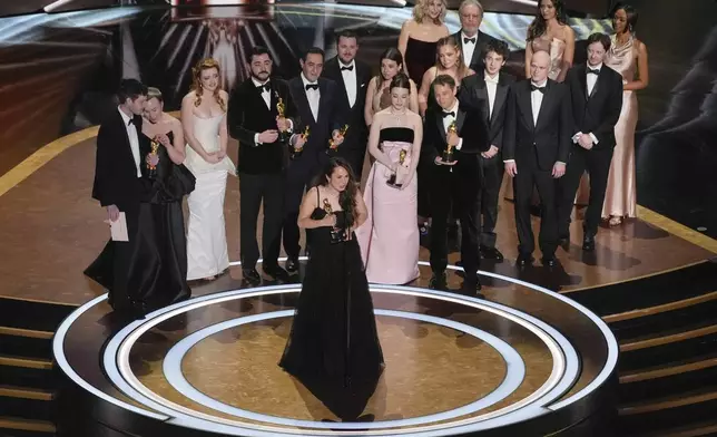 Samantha Quan, front center, accepts the award for best picture for "Anora" during the Oscars on Sunday, March 2, 2025, at the Dolby Theatre in Los Angeles. Alex Coco, from rear left, Darya Ekamasova, Lindsey Normington, Vache Tovmasyan, Karren Karagulian, Vincent Radwinsky, Luna Sofía Miranda, Mikey Madison, Sean Baker, x, Mark Eydelshteyn, Yura Borisov, Meg Ryan, and Billy Crystal look on from back. (AP Photo/Chris Pizzello)