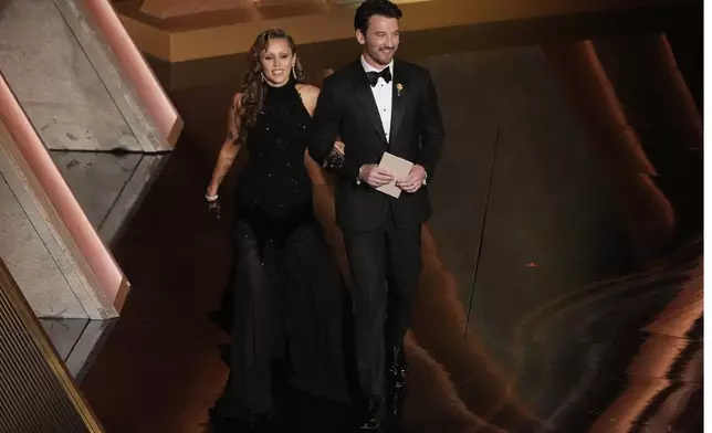 Miley Cyrus, left, and Miles Teller present the award for best sound during the Oscars on Sunday, March 2, 2025, at the Dolby Theatre in Los Angeles. (AP Photo/Chris Pizzello)