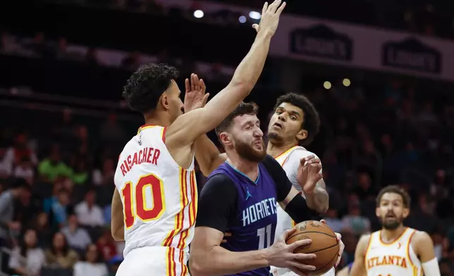 Charlotte Hornets center Jusuf Nurkic (11) fights through a double-team by Atlanta Hawks forwards Zaccharie Risacher (10) and Dominick Barlow during the first half of an NBA basketball game in Charlotte, N.C., Tuesday, March 18, 2025. (AP Photo/Nell Redmond)
