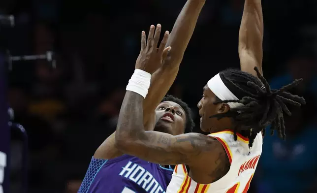 Atlanta Hawks guard Terance Mann, right, shoots against Charlotte Hornets forward Moussa Diabate during the first half of an NBA basketball game in Charlotte, N.C., Tuesday, March 18, 2025. (AP Photo/Nell Redmond)