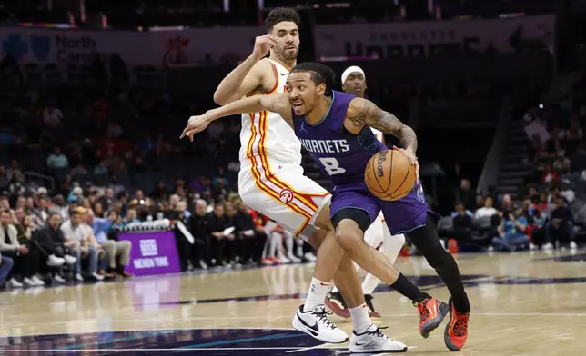 Charlotte Hornets guard Nick Smith Jr. (8) drives past Atlanta Hawks forward Georges Niang during the first half of an NBA basketball game in Charlotte, N.C., Tuesday, March 18, 2025. (AP Photo/Nell Redmond)