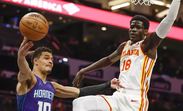Charlotte Hornets guard Josh Green (10) passes against Atlanta Hawks forward Mouhamed Gueye during the first half of an NBA basketball game in Charlotte, N.C., Tuesday, March 18, 2025. (AP Photo/Nell Redmond)
