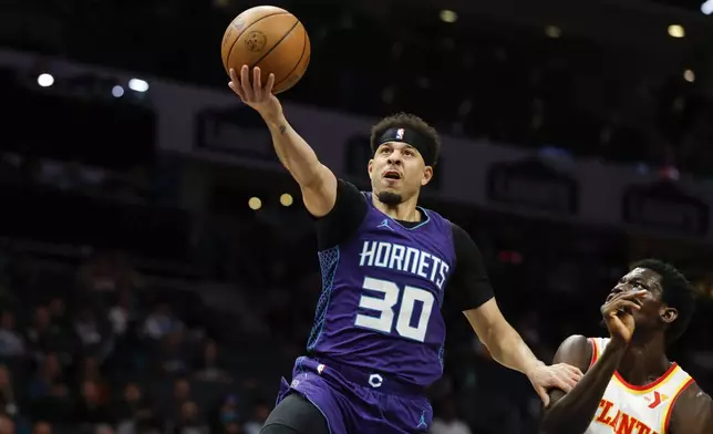 Charlotte Hornets guard Seth Curry (30) drives to the basket past Atlanta Hawks forward Mouhamed Gueye during the first half of an NBA basketball game in Charlotte, N.C., Tuesday, March 18, 2025. (AP Photo/Nell Redmond)