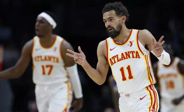 Atlanta Hawks guard Trae Young (11) gestures after making a three point basket against the Charlotte Hornets during the first half of an NBA basketball game in Charlotte, N.C., Tuesday, March 18, 2025. (AP Photo/Nell Redmond)