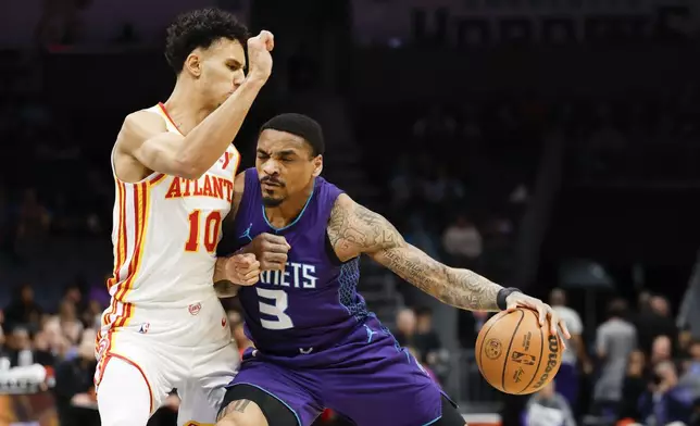 Charlotte Hornets guard DaQuan Jeffries (3) drives into Atlanta Hawks forward Zaccharie Risacher during the first half of an NBA basketball game in Charlotte, N.C., Tuesday, March 18, 2025. (AP Photo/Nell Redmond)