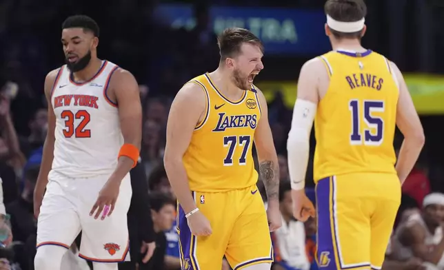 Los Angeles Lakers guard Luka Doncic, center, celebrates after scoring as New York Knicks center Karl-Anthony Towns, left, walks away and guard Austin Reaves stands by during the second half of an NBA basketball game Thursday, March 6, 2025, in Los Angeles. (AP Photo/Mark J. Terrill)