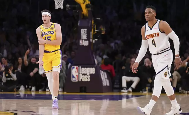 Los Angeles Lakers guard Austin Reaves, left, gestures after scoring as Denver Nuggets guard Russell Westbrook stands by during the first half of an NBA basketball game Wednesday, March 19, 2025, in Los Angeles. (AP Photo/Mark J. Terrill)