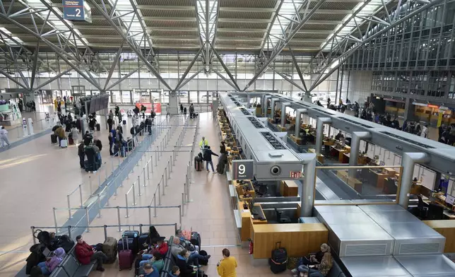 Passengers stand in front of counters at Hamburg Airport, Germany Sunday, March 9, 2025. (Georg Wendt/dpa via AP)