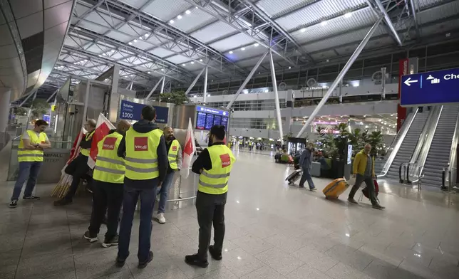 Striking members of the Verdi union stand in the departure area of the terminal building at Dusseldorf Airport, Germany Monday, March 10, 2025. (Christoph Reichwein/dpa via AP)