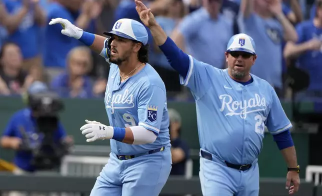 Kansas City Royals' Vinnie Pasquantino (9) celebrates with third base coach Vance Wilson after hitting a three-run home run during the third inning of a baseball game against the Cleveland Guardians Thursday, March 27, 2025, in Kansas City, Mo. (AP Photo/Charlie Riedel)