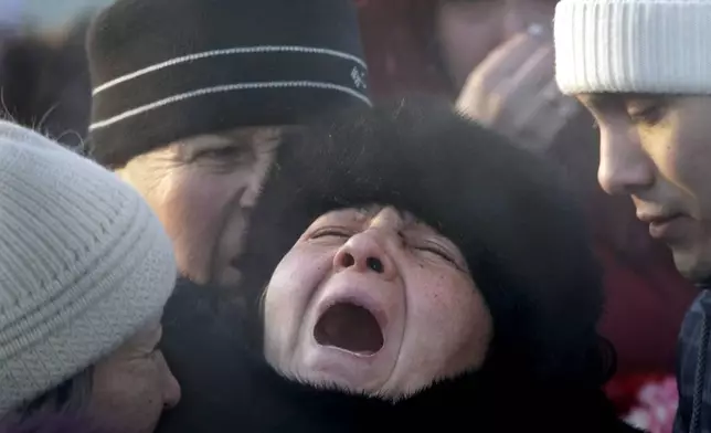 FILE - Mother of Liliya Kalashnikova, a victim of the night club fire, center, no name given, cries at her daughter's funeral at a cemetery in the Ural Mountains city of Perm, about 1,200 km (700 miles) east of Moscow, Monday, Dec. 7, 2009. (AP Photo/Mikhail Metzel, File)