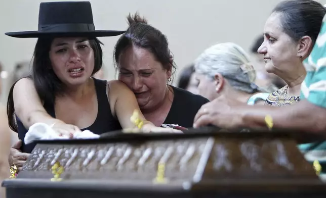 FILE - Relatives cry next to a coffin at a gymnasium where bodies were brought for identification in Santa Maria city, Rio Grande do Sul state, Brazil, Sunday, Jan. 27, 2013 (AP Photo/Nabor Goulart, File)