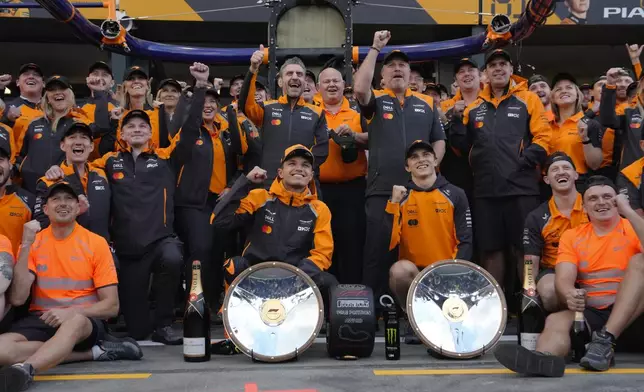 Race winner McLaren driver Lando Norris of Britain and teammate Oscar Piastri of Australia pose with their team following the Australian Formula One Grand Prix at Albert Park, in Melbourne, Australia, Sunday, March 16, 2025. (AP Photo/Asanka Brendon Ratnayake)