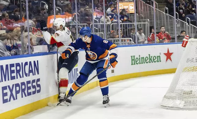 New York Islanders defenseman Noah Dobson (8) slams Florida Panthers center Anton Lundell, left, during the first period of an NHL hockey game, Sunday, March 16, 2025, in Elmont, N.Y. (AP Photo/Stefan Jeremiah)