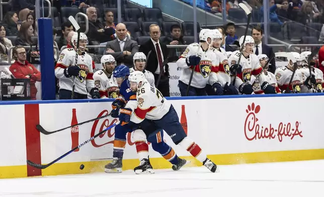 New York Islanders right wing Oliver Wahlstrom (26) and Florida Panther defenseman Uvis Balinskis, left, compete for the puck during the second period of an NHL hockey game, Sunday, March 16, 2025, in Elmont, N.Y. (AP Photo/Stefan Jeremiah)