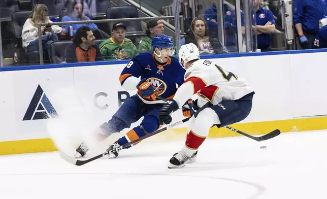 New York Islanders defenseman Alexander Romanov, left, and Florida Panthers defenseman Gustav Forsling, right, compete for the puck during the second period of an NHL hockey game, Sunday, March 16, 2025, in Elmont, N.Y. (AP Photo/Stefan Jeremiah)