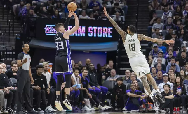 Sacramento Kings forward Jake LaRavia (33) attempts a three-pointer over Milwaukee Bucks forward Kyle Kuzma (18) during the first half of an NBA basketball game Saturday, March 22, 2025, in Sacramento, Calif. (AP Photo/Sara Nevis)