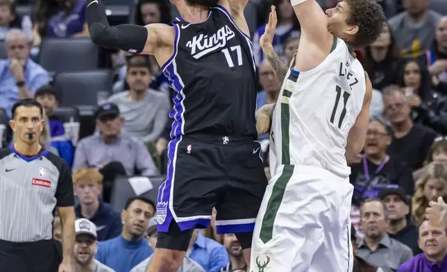 Sacramento Kings center Jonas Valanciunas (17) goes up for a layup and draws the foul on Milwaukee Bucks center Brook Lopez (11) during the first half of an NBA basketball game Saturday, March 22, 2025, in Sacramento, Calif. (AP Photo/Sara Nevis)