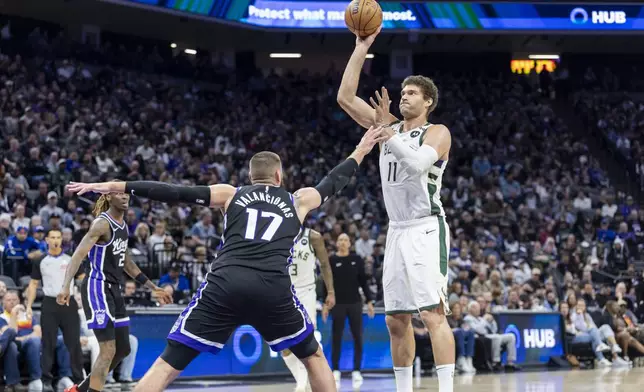 Milwaukee Bucks center Brook Lopez (11) makes a shot and draws the foul on Sacramento Kings center Jonas Valanciunas (17) during the first half of an NBA basketball game Saturday, March 22, 2025, in Sacramento, Calif. (AP Photo/Sara Nevis)