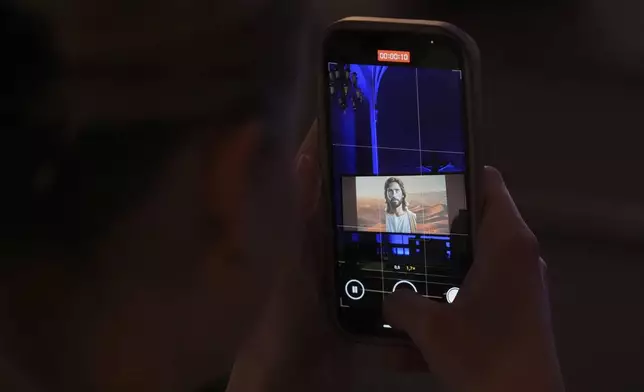 A person takes a video with a cellphone during an AI-created service at St. Paul's Lutheran church in Helsinki, Finland, Tuesday, March 4, 2025. (AP Photo/Sergei Grits)