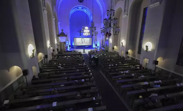 People watch an AI-created service at St. Paul's Lutheran church in Helsinki, Finland, Tuesday, March 4, 2025. (AP Photo/Sergei Grits)