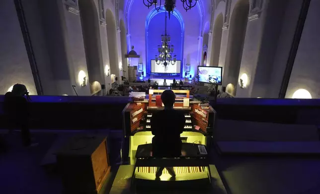 People watch an AI-created service at St. Paul's Lutheran church in Helsinki, Finland, Tuesday, March 4, 2025. (AP Photo/Sergei Grits)