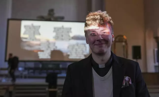 The Rev. Petja Kopperoinen poses for a photo, lit by the beams of a projector, during a rehearsal for an AI-created service at St. Paul's Lutheran church in Helsinki, Finland, Tuesday, March 4, 2025. (AP Photo/Sergei Grits)
