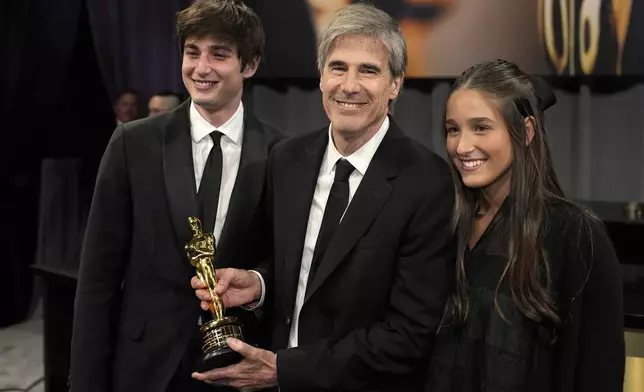 Vicente Salles, left, Walter Salles, winner of the award for "I'm Still Here" from Brazil, for best international feature film, and Helena Salles attends the Governors Ball after the Oscars on Sunday, March 2, 2025, in Los Angeles. (AP Photo/John Locher)