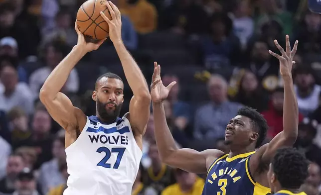 Minnesota Timberwolves center Rudy Gobert (27) grabs a rebound over Indiana Pacers center Thomas Bryant (3) during the first half of an NBA basketball game in Indianapolis, Monday, March 24, 2025. (AP Photo/Michael Conroy)