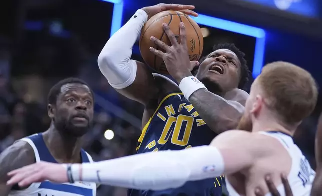 Indiana Pacers guard Bennedict Mathurin (00) is fouled as he shoots over Minnesota Timberwolves guard Donte DiVincenzo (0) during the first half of an NBA basketball game in Indianapolis, Monday, March 24, 2025. (AP Photo/Michael Conroy)