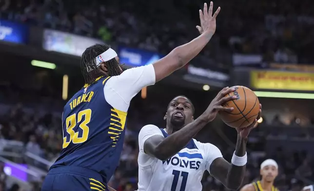 Minnesota Timberwolves center Naz Reid (11) shoots over Indiana Pacers center Myles Turner (33) during the second half of an NBA basketball game in Indianapolis, Monday, March 24, 2025. (AP Photo/Michael Conroy)