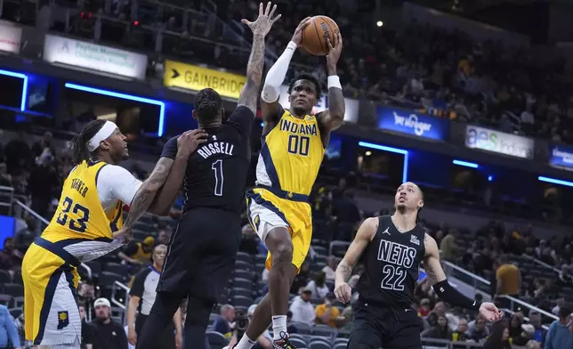 Indiana Pacers guard Bennedict Mathurin (00) shoots around Brooklyn Nets guard D'Angelo Russell (1) during the second half of an NBA basketball game in Indianapolis, Thursday, March 20, 2025. (AP Photo/Michael Conroy)