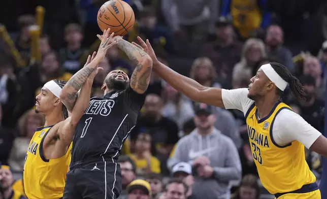 Brooklyn Nets guard D'Angelo Russell (1) is fouled by Indiana Pacers guard Andrew Nembhard (2) as he shoots over Indiana Pacers center Myles Turner (33) during overtime in an NBA basketball game in Indianapolis, Thursday, March 20, 2025. (AP Photo/Michael Conroy)