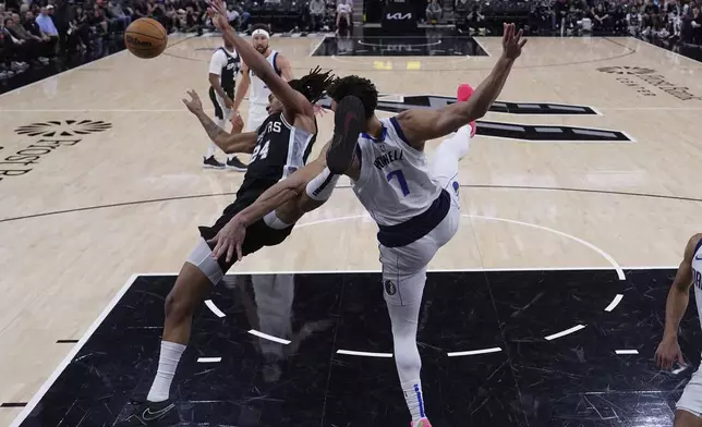 San Antonio Spurs guard Devin Vassell (24) is blocked by Dallas Mavericks center Dwight Powell (7) as he drives to the basket during the second half of an NBA basketball game in San Antonio, Monday, March 10, 2025. (AP Photo/Eric Gay)