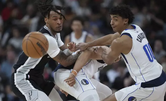 San Antonio Spurs guard Stephon Castle, left, and Dallas Mavericks guard Max Christie, right, scramble for a loose ball during the second half of an NBA basketball game in San Antonio, Monday, March 10, 2025. (AP Photo/Eric Gay)
