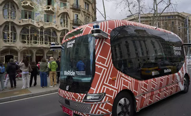 A driverless mini-bus, presented by WeRide and Renault Group, drives by Casa Batlló, designed by Antoni Gaudí, in Barcelona downtown, Wednesday, March 12, 2025. (AP Photo/Emilio Morenatti)