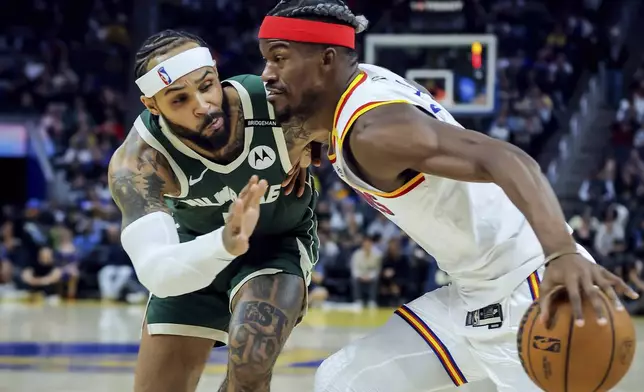 Golden State Warriors' Jimmy Butler, right, drives to the basket against Milwaukee Bucks' Gary Trent Jr. (5) during the first half of an NBA basketball game in San Francisco, on Tuesday, March 18, 2025. (Carlos Avila Gonzalez/San Francisco Chronicle via AP)