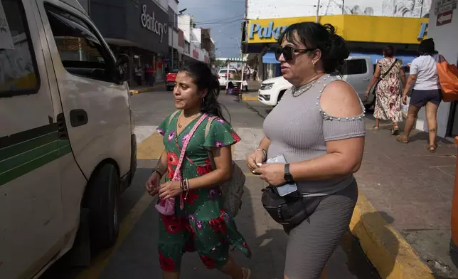 Transgender woman Ana Esquivel, right, who applied for asylum in Mexico, boards a bus in Tapachula, Chiapas state, Mexico, Tuesday, March 11, 2025. (AP Photo/Moises Castillo)