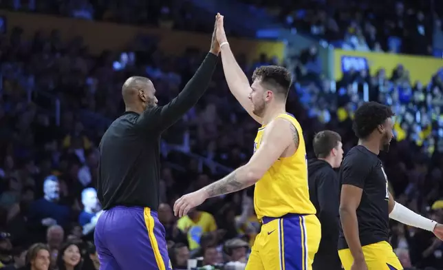 Los Angeles Lakers' LeBron James, left, and Luka Doncic high-five during the first half of an NBA basketball game against the New Orleans Pelicans Tuesday, March 4, 2025, in Los Angeles. (AP Photo/Jae C. Hong)