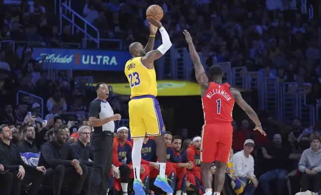 Los Angeles Lakers forward LeBron James, left, makes a 3-point basket over New Orleans Pelicans forward Zion Williamson (1) to go over the 50,000 career point mark during the first half of an NBA basketball game Tuesday, March 4, 2025, in Los Angeles. (AP Photo/Jae C. Hong)