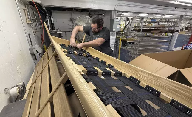 Built by Newport furniture company employee Eric Benware puts webbing on a sofa after the business's owner, Dave Laforce, who sources material from Canada, attended a roundtable event with U.S. Sen. Peter Welch of Vermont and Marie-Claude Bibeau, a Canadian member of parliament, to discuss the Trump administration's tariffs, Tuesday, March 18, 2025, in Newport, Vt. (AP Photo/Amanda Swinhart)